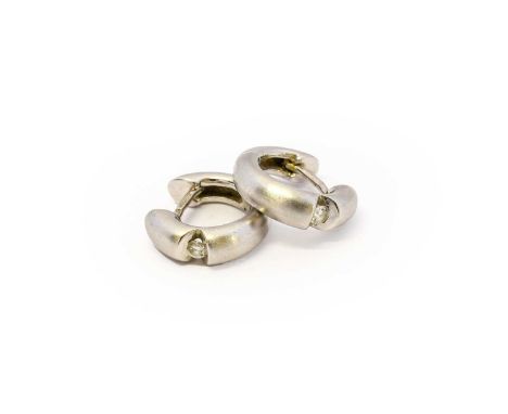 A pair of 18 carat white gold diamond hoop earrings, the round brilliant cut diamond tension set within a matte hinged hoop, 