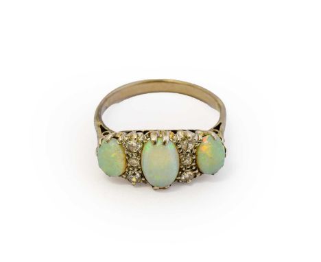 An opal and diamond ring, three graduated oval cabochon opals spaced by trios of old cut and eight-cut diamonds, in white cla