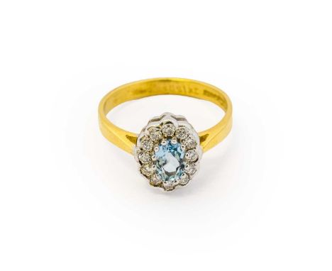 An 18 carat gold aquamarine and diamond cluster ring, the oval cut aquamarine within a border of round brilliant cut diamonds