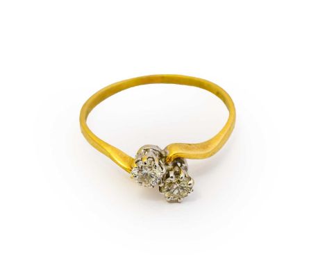 An 18 carat gold diamond two stone twist ring, the round brilliant cut diamonds in white claw settings, to a yellow twist sho