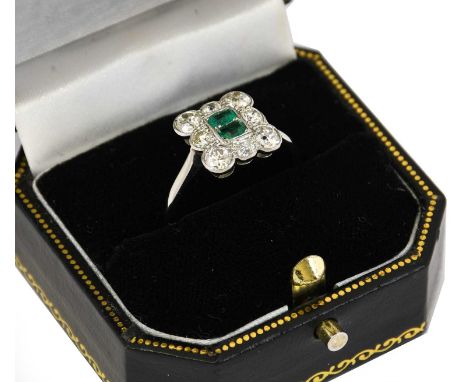 An emerald and diamond cluster ring, two emerald-cut emeralds within a border of old cut diamonds, in white millegrain settin