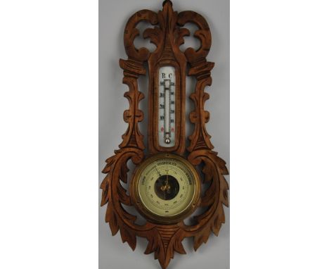 An early 20th Century German barometer, within a foliate carved wood surround. H. 40cm