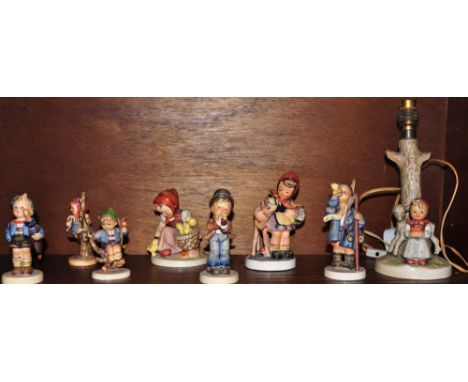 An assortment of seven Hummel figurines together with a similar table lamp (AF)