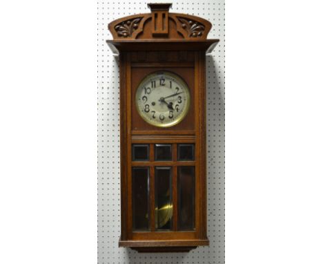 An Art Deco style oak cased wall clock, silvered dial, Arabic numerals, eight day manual movement, carved shaped cornice, c.1