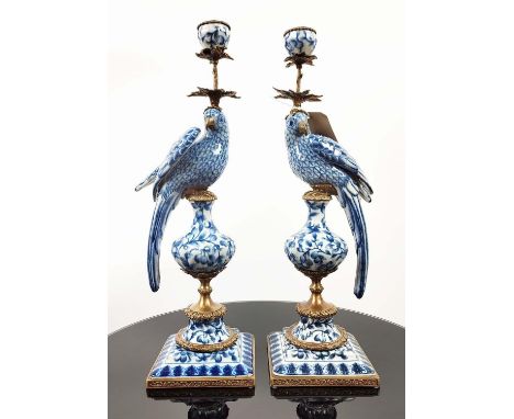 CANDLESTICKS, a pair, in the form of parrots perched on pedestals, blue and white ceramic, gilt metal mounts, 49cm H. (2) 
