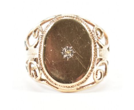 A hallmarked 9ct gold and diamond signet ring. The ring having an oval diamond set cartouche having scrolled filigree style s