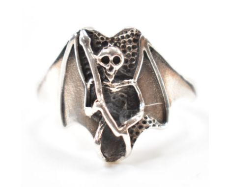 A silver skeleton dress ring. The ring having moulded details depicting a skeleton with bat wings to the head. Marked 925, si
