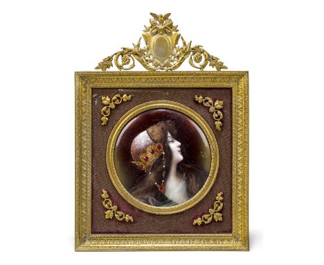A French enamel portrait plaque of a maiden, early 20th century, depicted wearing a jewelled cap, gilt monogram, in a gilt-br