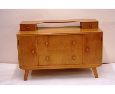 A 1960's light oak dressing chest, fitted two drawers flanked by cupboards, 114cm wide x 76cm high