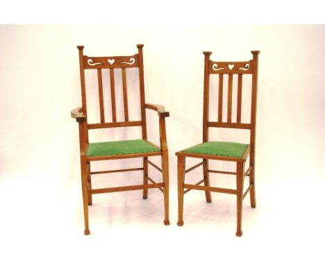 A set of six light oak Arts & Crafts dining chairs, four standard, two carvers, the back supports with heart and swirl design