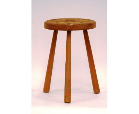 A three legged stool, the circular top carved with stylised flowerhead design, 25cm dia. x 36cm high