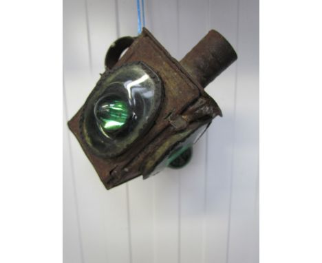 A vintage candle lantern with three green niple lenses 