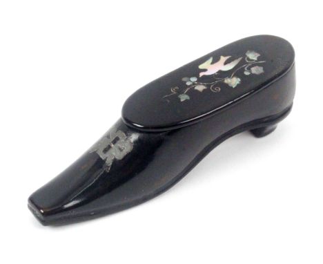 A papier mache shoe form snuff box, with white metal inlaid bow, the hinged cover inlaid with mother of pearl bird over a wir