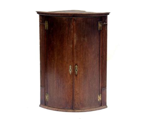 A  GEORGE III OAK BOW FRONTED CORNER CUPBOARD, 94CM H