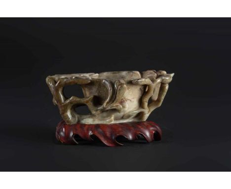  A jade brush washer carved in the shape of a magnolia branchChina, Qing dynasty, 19th century Wooden baseCm 17,00 x 6,50 22.
