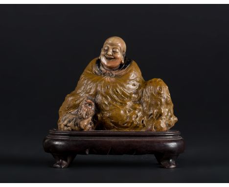  A soapstone carving of a Lohan on a wooden stand China, Qing dynasty, 19th century Cm 13,50 x 11,00 22.00 % buyer's premium 