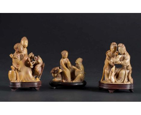  Set of three soapstones carved with ladies playing the flute, playing with animals and sitting on an ox on wooden standsChin
