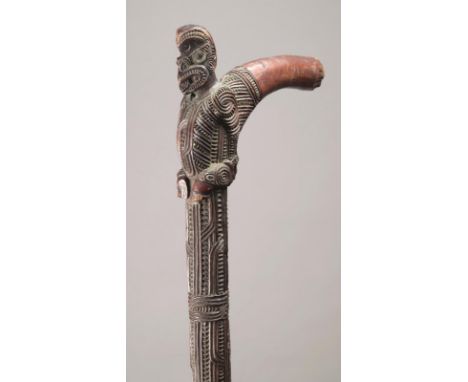 A Maori cane New Zealand with carved linear and notch decoration, with a seated tiki finial with haliotis shell inset eyes on