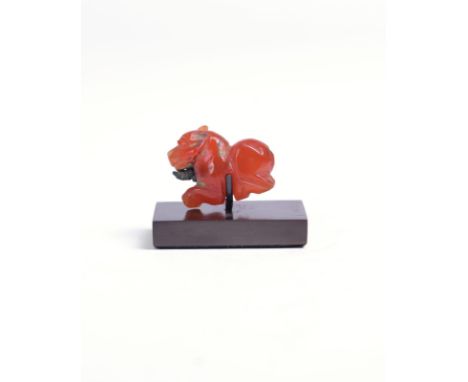 An Egyptian carnelian recumbent lion amulet Late Period with remains of a metal wire through the body, 2.5cm long, on a stand