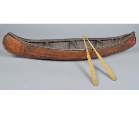 A Cree model canoe wood, birch bark and fibre binding, with a banded interior and with seat boards, 76cm long, with two paint