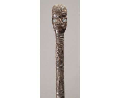 A Maori cane New Zealand with a tattooed head finial with haliotis shell inset eyes, the shaft part carved linear and notched