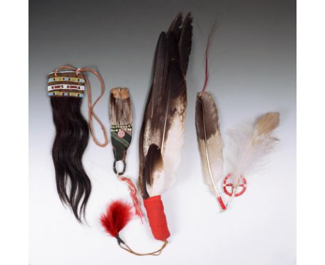A Plains fan  eagle feathers with cloth binding and with two tin cone and red feather tassels,  89cm long,  a Sioux quill dis