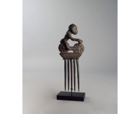 A Yoruba comb Nigeria with a cyclist surmount and five tines, 28cm high, on a stand. (2)