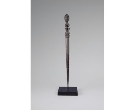 A Dayak pig trap stick Borneo, Indonesia with a seated ancestor figural finial and a tapering shaft, 63cm high, on a stand. (