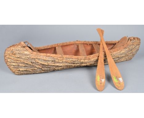 An Iroquois model canoe cedar and birch bark with fibre binding, with seat boards and back rest, with a pair of paddles with 