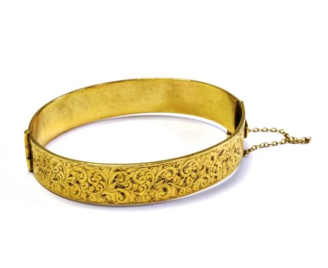 9CT GOLD METAL CORE BANGLE 12.6mm wide with scroll and foliate decoration to front, hinge to one side and concealed tongue cl