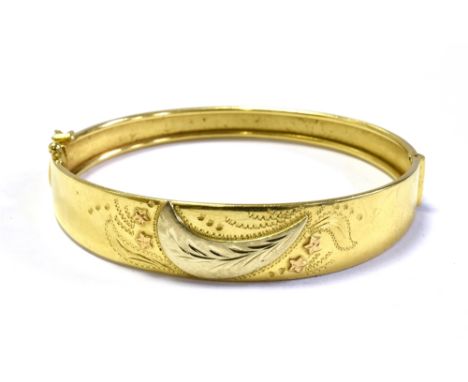 18CT GOLD ENGRAVED BANGLE 12.9mm foliate and scroll engraved front, hinge to one side and plain back, secured with a tongue i
