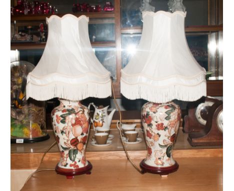 Pair Of Ceramic Table Lamps the bases with floral decoration & berries on white ground. Both with cream shades. 27'' in heigh