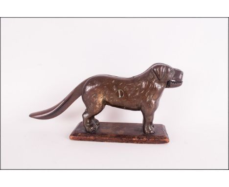 A Late 19th Century Cast Iron Novelty Nut Cracker In The Form of a Long Tailed Dog, Supported on an Oak Plinth. 5.5 Inches Hi