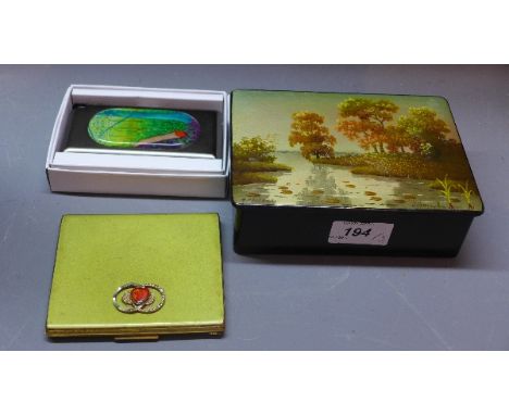 A Russian black lacquered box with hand painted lid depicting a lake scene, signed, together with a gilt metal cigarette case