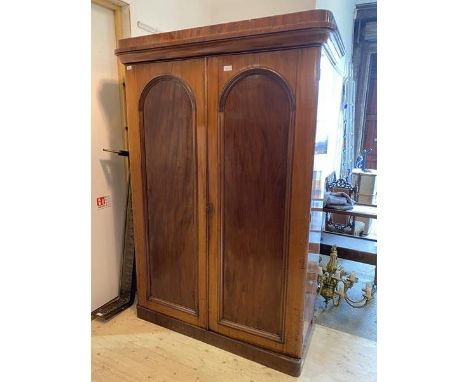 A Victorian mahogany double wardrobe with caddy and cavetto cornice over twin arched panel doors enclosing hanging hooks and 