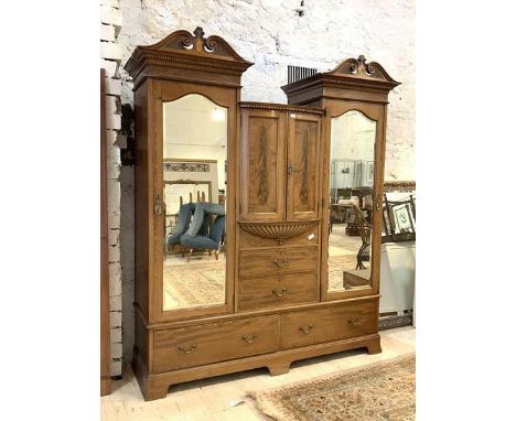 A late 19thc mahogany three part wardrobe, the twin pediments with boxwood paterae over dental cornice, the section centre wi