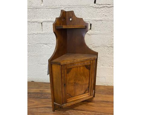 An Edwardian walnut tabletop corner cabinet, the moulded edge united by upper shelf over cabinet with panelled door, unfitted