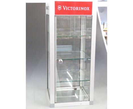 A glazed and brushed steel haberdashery/shopfitting display cabinet with Maglite and Victorinox decals and four glazed shelve