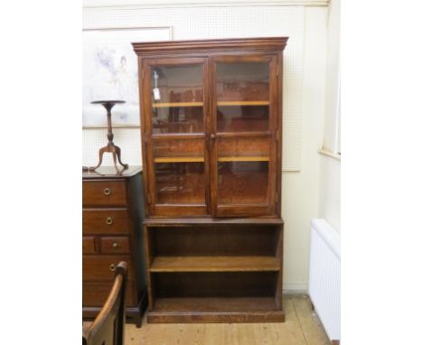 An early 20th century solid, dark oak bookcase, pair of glazed doors enclosing two shelves, further open shelf beneath, 3ft. 