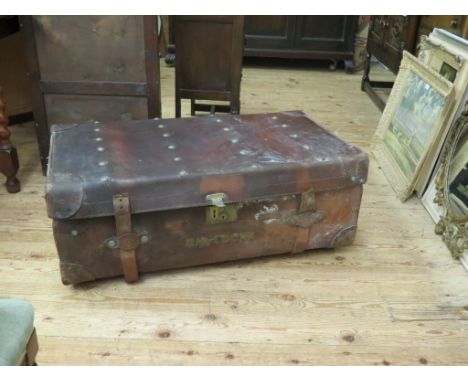 A large, early 20th century leather trunk, with side carrying handles