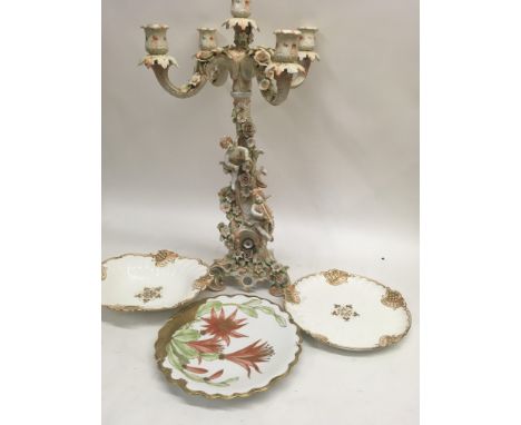 A German candelabra decorated with cherubs flowers and foliage, together with three plates - NO RESERVE