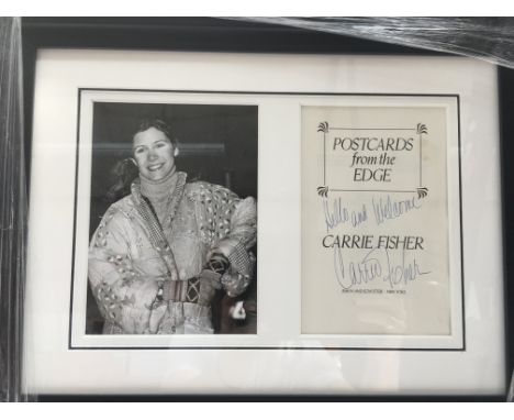 A framed and glazed Carrie Fisher signed book page from her book 'Postcards From The Edge', displayed with a monochrome print