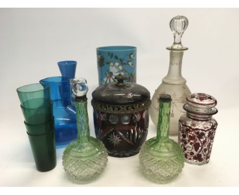 A collection of coloured glass items comprising a decanter with overlaid swag decoration, ruby glass jar and cover and other 