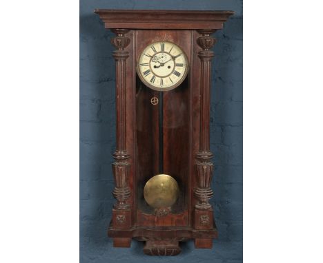 A large carved mahogany 8 day wall clock with enamel dial and roman numeral markers.  Some of the wood at the top of the cloc