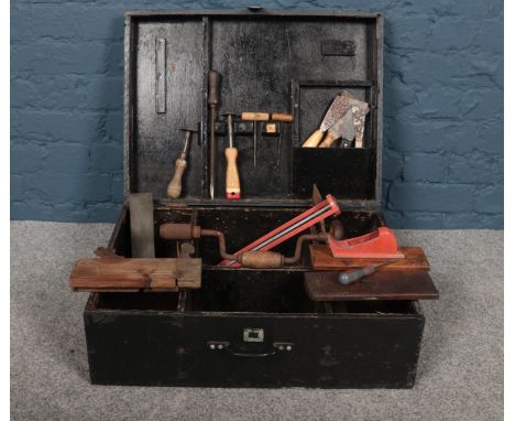 A large hinged black wooden compartmentalised tool box, with various vintage tools inside such as a hand drill, three wooden 