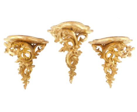 A pair of rococo style gilt wood wall shelves, of serpentine form, raised on fillet scroll supports, 34cm high., together wit