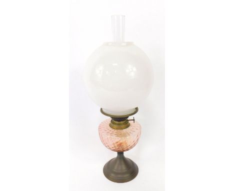 An early 20thC tin and glass oil lamp, with a moulded pink glass reservoir, clear glass chimney and a white glass globular sh