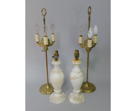 A pair of brass three light table lamps, with ring handles, and a pair of alabaster baluster table lamps.