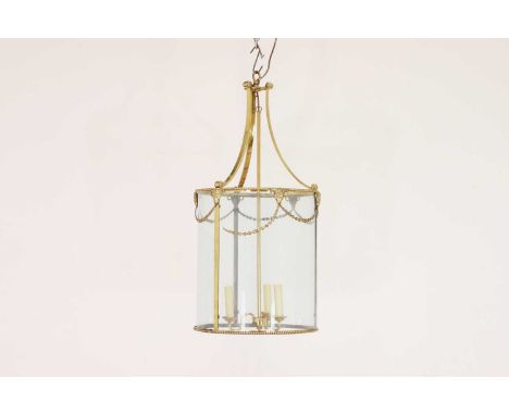 A brass lantern,20th century, with three curved glass panels enclosing three lights, mounted with ram masks and foliate swags