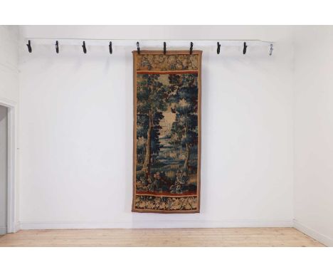 A verdure tapestry fragment, late 17th century, Flemish, decorated with rabbits in a clearing with a castle beyond, 236 x 100